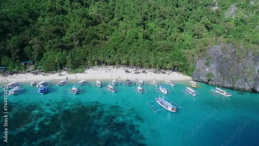 Seven Commandos Beach in Palawan, Sightseeing Place. Tour A in El Nido, Philippines. Serene white sand beach with clear turquoise water, palm trees rock formations in Background. Drone Seven Commandos Beach in Palawan, Sightseeing Place. Tour A in El Nido, Philippines. Serene white sand beach with clear turquoise water, palm trees rock formations in Background. Drone
