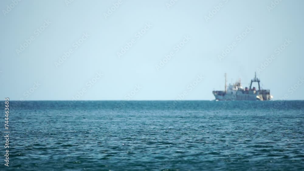 Fishing boat trawler catches fish while sailing on sea. A commercial fishing boat on the horizon in a distance sail to catch school of fish on calm sea surface in summer. Commercial catch of sea fish. Fishing boat trawler catches fish while sailing on sea. A commercial fishing boat on the horizon in a distance sail to catch school of fish on calm sea surface in summer. Commercial catch of sea fish.