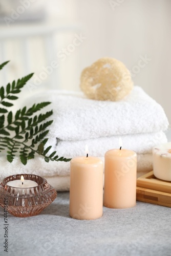 Spa composition. Burning candles  soap  towels and loofah on soft grey surface