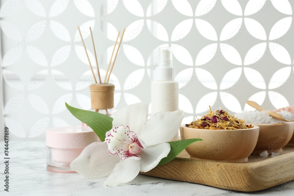 Beautiful composition with different spa products and orchid on white marble table