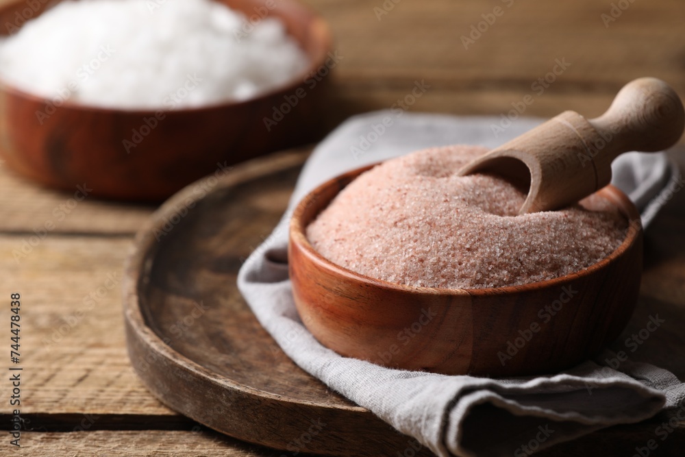 Different salt and scoop in bowl on wooden table, closeup. Space for text Different salt and scoop in bowl on wooden table, closeup. Space for text