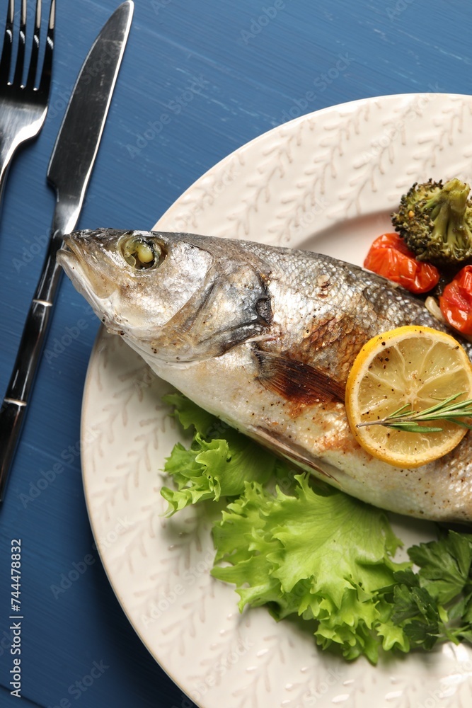 Delicious baked fish and vegetables served on blue wooden table, top view Delicious baked fish and vegetables served on blue wooden table, top view