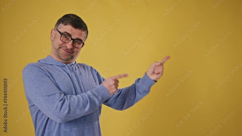 Mature man pointing to the left on a yellow background Mature man pointing to the left on a yellow background