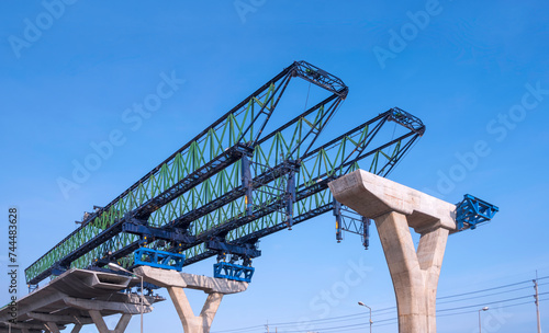 Launching gantry structure for installing concrete typical segment joint on foundation of elevated expressway in road construction site against blue sky background