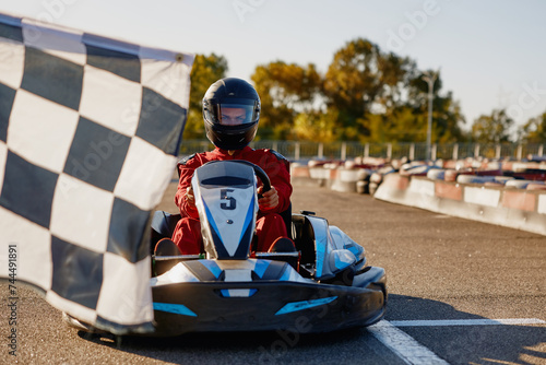 Fotografie Go-kart driver crossing at finish line moving to checkered racing flag