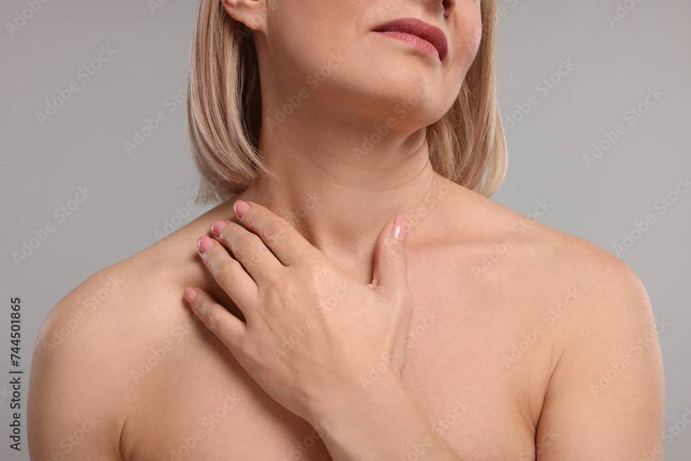 Woman touching her neck on grey background, closeup Woman touching her neck on grey background, closeup