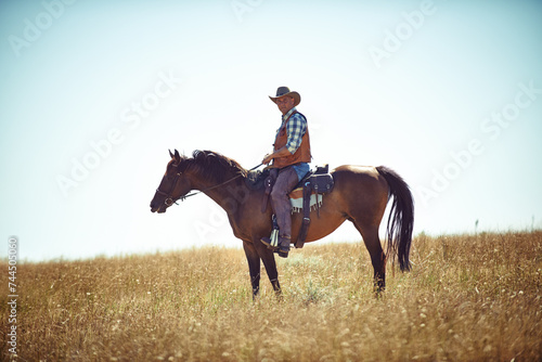 Man, horse and countryside field as cowboy for adventure riding in Texas meadow for explore farm, exercise or training. Male person, animal and stallion in rural environment on saddle, ranch or hobby