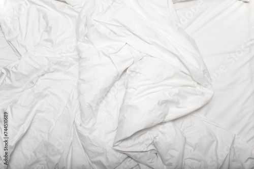 Morning time, messy, crumpled used white blanket on a bed, top view