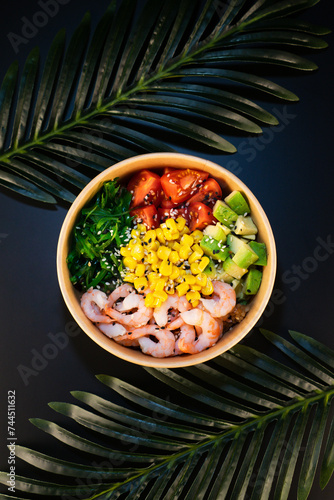 bowl with shrimp, avocado, corn, tomato and chuka, on a dark background
