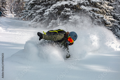 Powder snowboarding. Freeride snowboarder girl riding off-trail fresh powder snow high in the mountains.