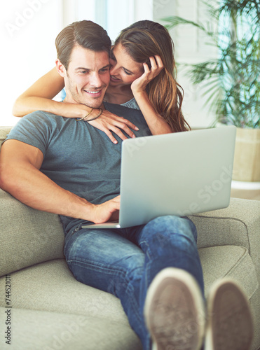 Laptop, bonding and woman hugging man on sofa networking on social media, website or internet. Happy, love and female person embracing husband reading online blog with computer in living room at home