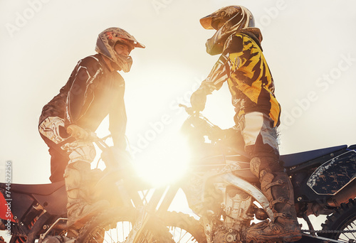 Sport, racer or people on motorcycle outdoor on dirt road with relax after driving, challenge or competition. Motocross, lens flare or dirtbike driver or friends on offroad course or path for sunset photo
