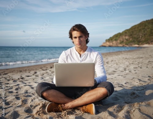 An young man sitting on a beach with laptop and working remotely