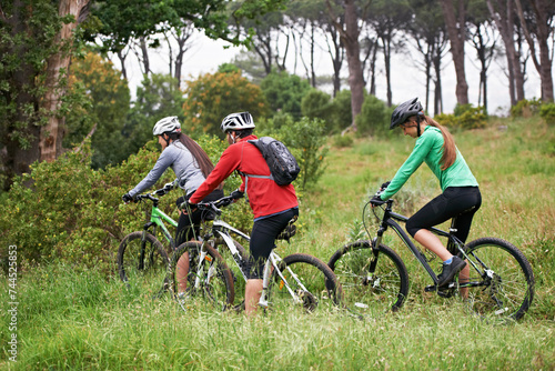 Cycling, sports and friends in nature for fitness, race and journey with competition or training on path in forest. Group of people or athlete on bicycle for exercise, health and cardio on mountains