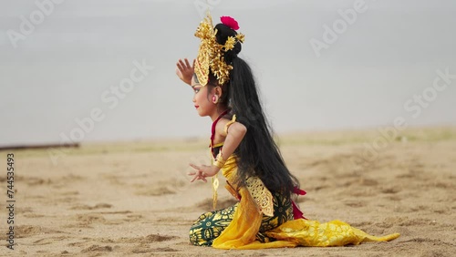 Female balinese dancer performing oleg dance in traditional fabric known as prada photo