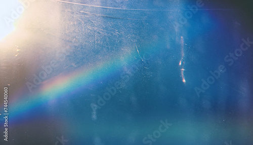 Dust scratches overlay. Old film effect. Blue distressed faded glass with smeared dirt stains colorful rainbow lens flare design. sun light abstract background texture