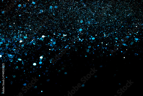 Blue sparkles or glitter over black cosmic abstract background.