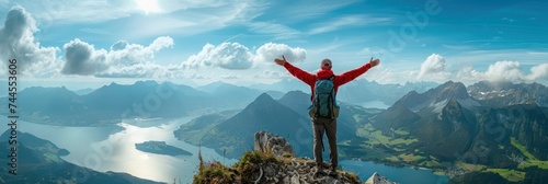 A mountain climber at the mountain top raises his hands. He is overlooking a stunning landscape. © Simon