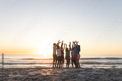 Diverse group celebrates on the beach at sunset
