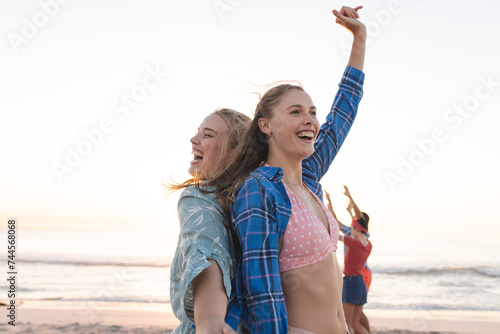Joyful young women celebrate at the beach, with copy space