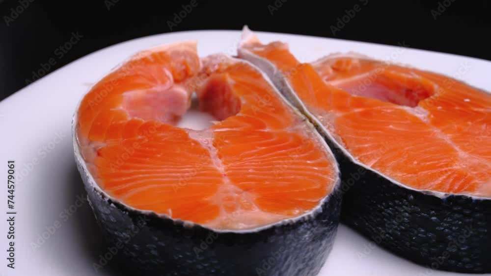 Raw salmon tenderloin on a white plate on a black background. Salmon. Seafood.Trout Steak Raw salmon tenderloin on a white plate on a black background. Salmon. Seafood.Trout Steak