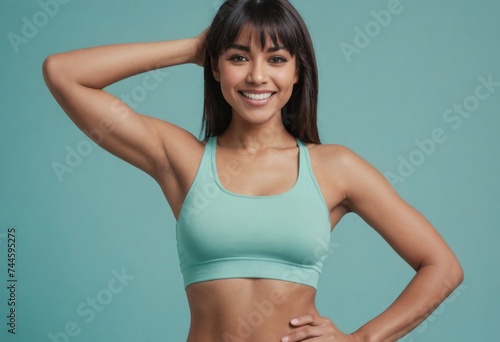 A fit woman in a sports bra poses with one hand on her hip  her confident smile and athletic build indicative of an active lifestyle.