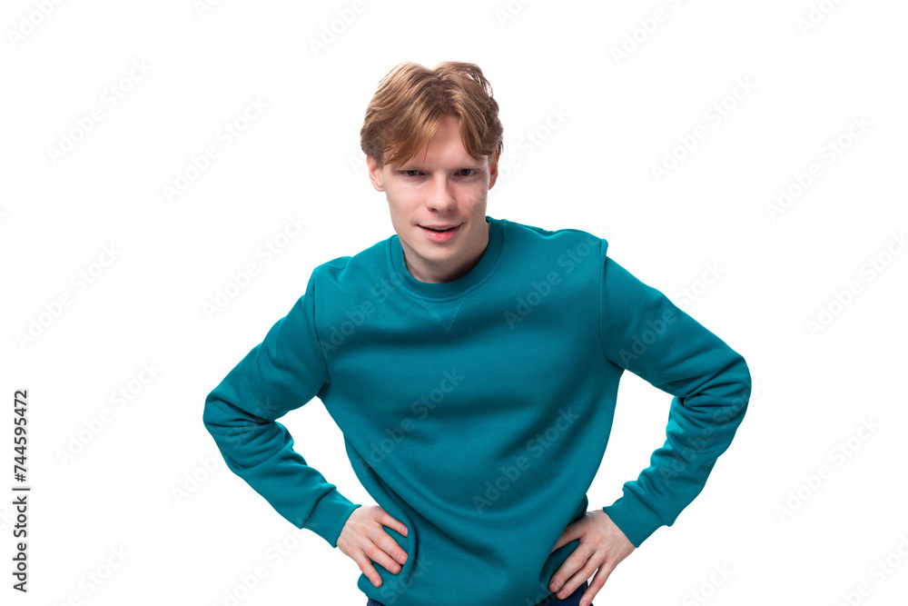 young surprised guy with short red hair dressed in a blue pullover on a white background young surprised guy with short red hair dressed in a blue pullover on a white background