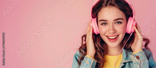 Young positive woman in big headphones on a bright background listening to music or a podcast, banner with copyspace for text