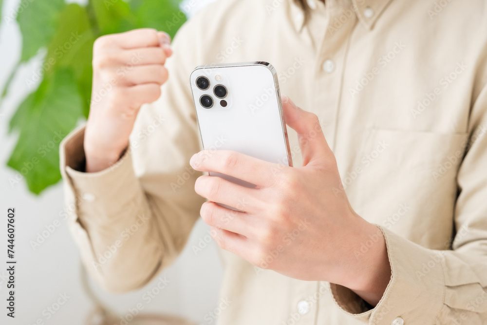 スマホを持ってガッツポーズする男性