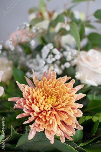 Details of a large bridal table floral centerpiece with focus on a large orange chrysanthemum, elegant flower arrangement brightening up the space: a restaurant or a reception area for the wedding day