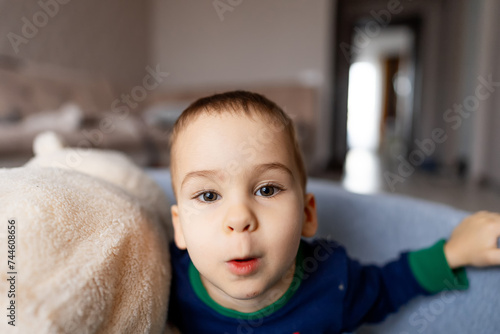 Cute little boy is lying on the couch and making funny face