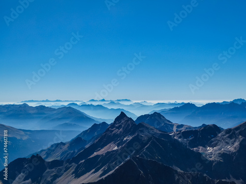 Panoramic view from majestic mountain peak of Hochschober, Schober Group, High Tauern National Park, East Tyrol, Austria. Wanderlust Austrian Alps in summer. Misty rugged ridges against clear blue sky © Chris