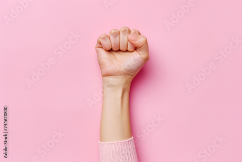 Girl power and woman empowerment concept. Woman raised fist isolated on pink background