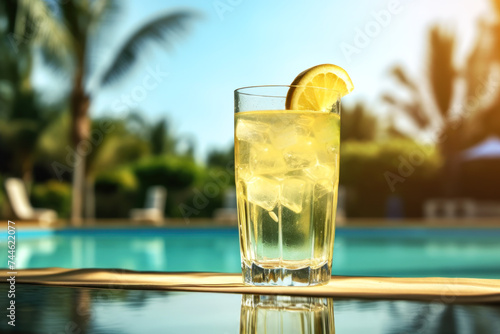 Refreshing lemon-infused water gleams in a glass by the azure pool