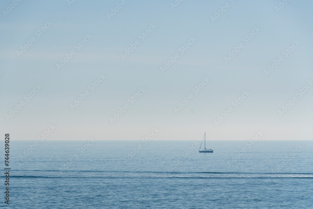 sailing ship with sails lowered, the horizon in the background and the sea calm.