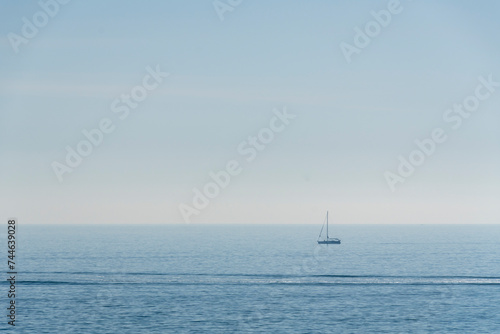 sailing ship with sails lowered, the horizon in the background and the sea calm.