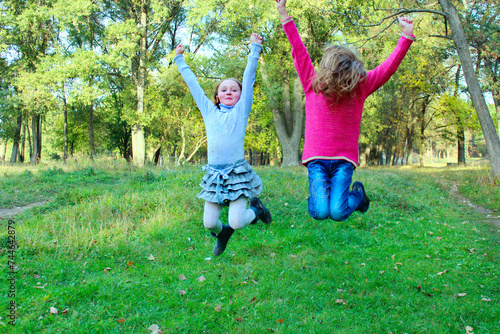 Young sisters jump in park. Happy childhood. Hovering in the air