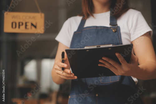 Startup successful small business owner sme beauty girl stand with tablet smartphone in coffee shop restaurant. Portrait of asian tan woman barista cafe owner. SME entrepreneur seller business concept
