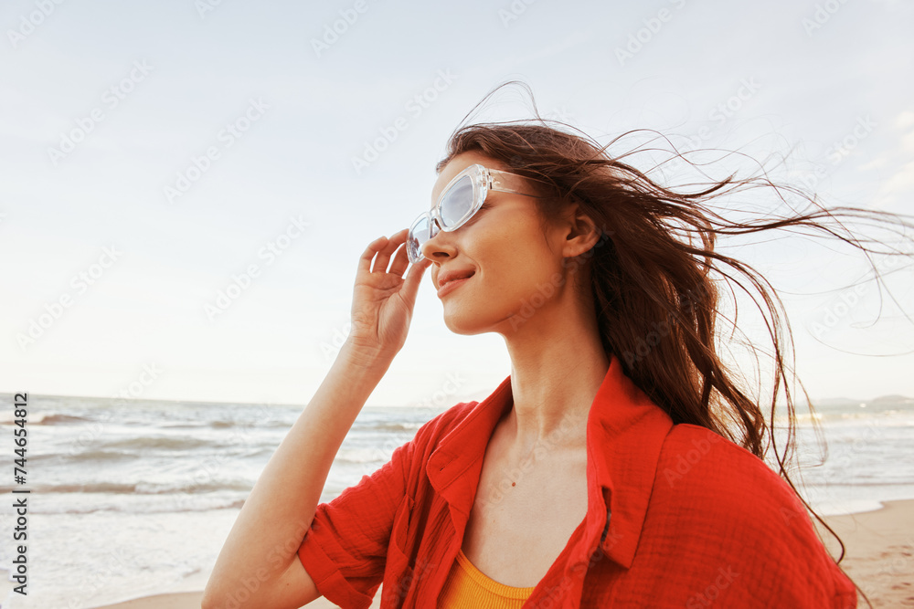 Smiling Woman with Sunglasses Enjoying Colorful Sunset by the Sea: Portrait of Freedom and Joy Smiling Woman with Sunglasses Enjoying Colorful Sunset by the Sea: Portrait of Freedom and Joy
