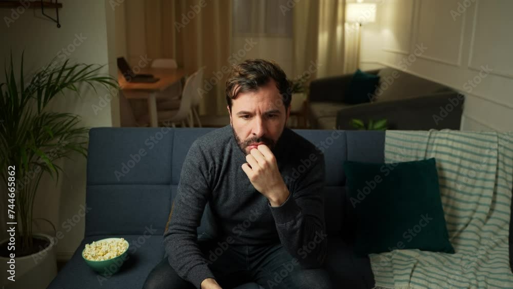 Man in his 30s looking really bored while trying to find something good on TV Man in his 30s looking really bored while trying to find something good on TV