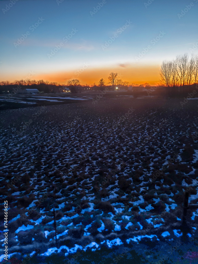 Fototapeta premium Sunset Over Farmland Partially Covered with Snow, Plain City, Ohio