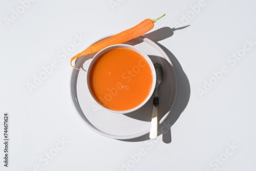 Sopa de zanahoria en un plato sobre fondo gris y blanco. Vista superior photo