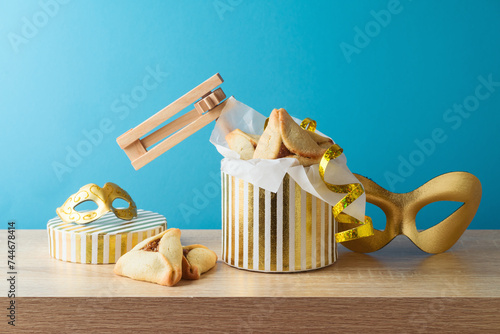 Jewish holiday Purim concept with hamantaschen cookies and golden carnival mask on wooden table over blue background