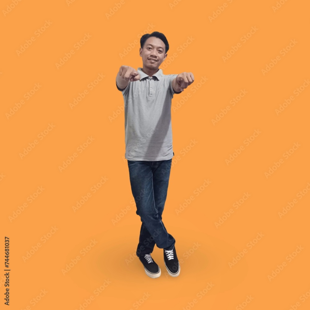 Full length image of cheerful man in his 30s wearing t-shirt and jeans showing finger while posing and smiling isolated on orange background Full length image of cheerful man in his 30s wearing t-shirt and jeans showing finger while posing and smiling isolated on orange background