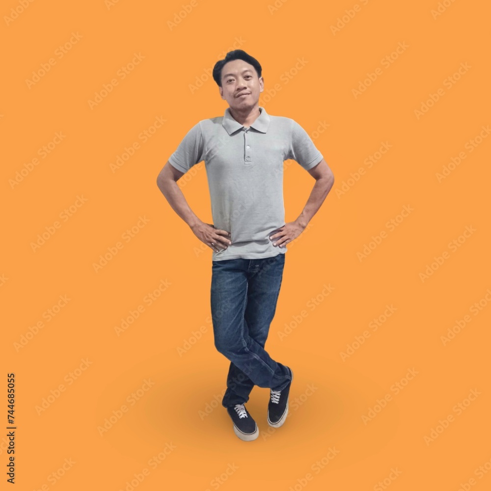 Full length image of Handsome man in his 30s wearing a t-shirt and jeans laughing while standing isolated on an orange background Full length image of Handsome man in his 30s wearing a t-shirt and jeans laughing while standing isolated on an orange background
