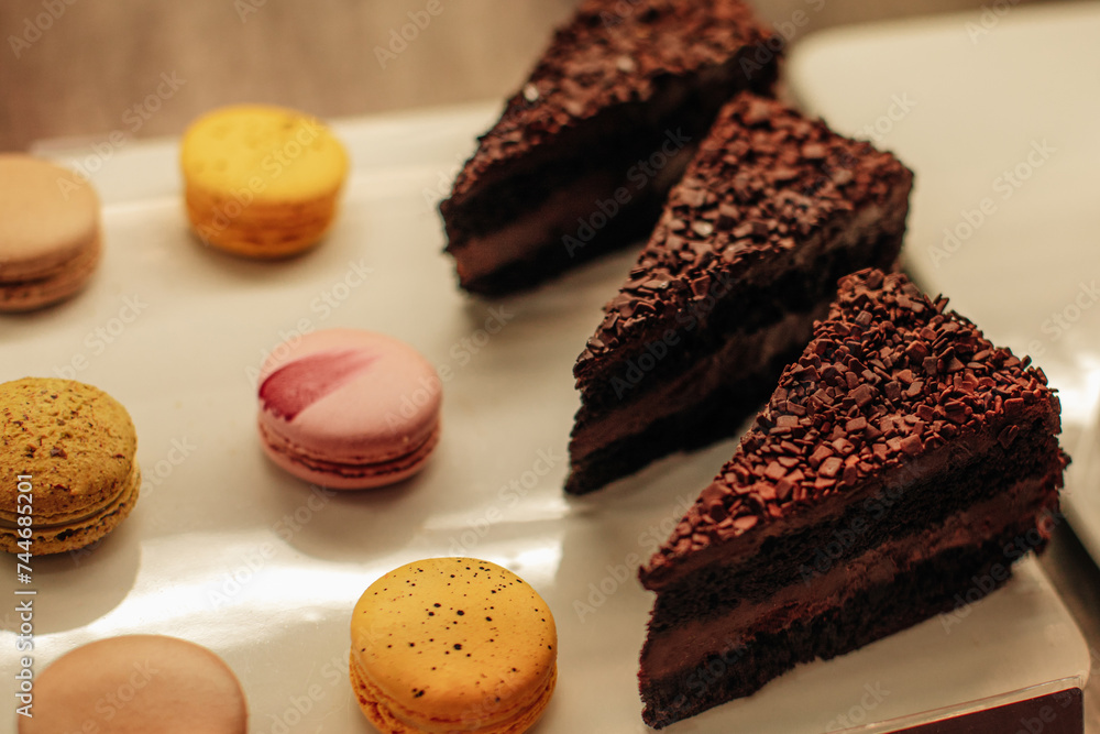 Delicious piece of cake with chocolate chips and filling and french macarons