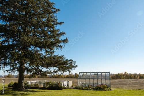 Photo of a greenhouse on a large farm in the afternoon with crops behind it