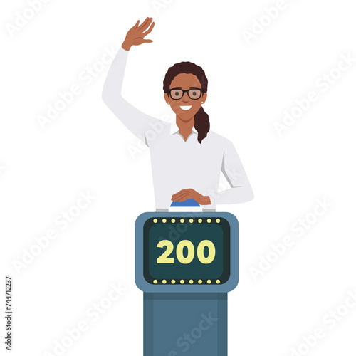 Young woman playing quiz game answering question standing at the stand with button. Girl pressed the buzzer first and raised hand up in the light of spotlight