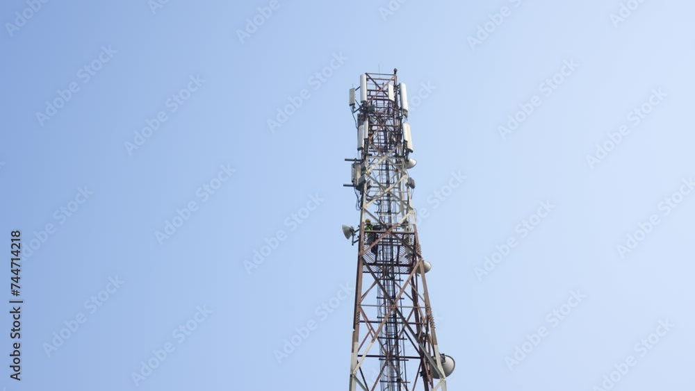 Technician climbing a network tower to fix it. Skilled work that technicians do to keep our communication networks running smoothly Technician climbing a network tower to fix it. Skilled work that technicians do to keep our communication networks running smoothly