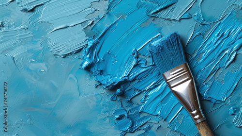 a paintbrush sitting on top of a blue paint covered floor next to a blue and white paint smudge. photo